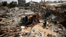 Palestinians sit in a makeshift tent amid the rubble of their houses which were destroyed by Israeli air strikes, Gaza, May 23, 2021