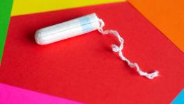 Feminine hygiene tampon on red, pink, orange background, close up 