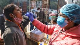 A healthcare worker collects a swab sample of a passenger for the COVID-19 test as the country sees an Omicron-driven Coronavirus surge, at New Delhi Railway station