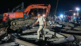 A police pesonnel crosses the mangled railway tracks during a rescue and search operation after the triple train mishap that claimed at least 261 people and left over 900 injured, in Balasore district, Odisha, Saturday, June 3, 2023.