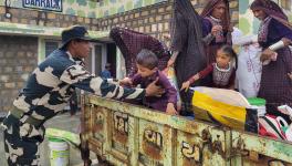 A BSF officer helps a child to get down from a tractor as evacuation process is underway ahead of the expected landfall of Cyclone Biparjoy, at Gunau village of kutch district, Wednesday, June 14, 2023.