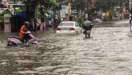 Commuters wade across a water-logged street surrounding the Ernakulam city after monsoon rainfall, in Kochi on Monday, July 16, 2018. 