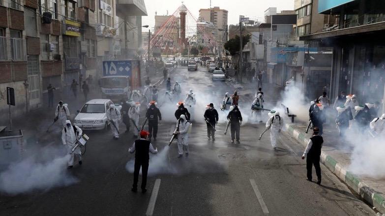 Firefighters disinfect a street in Tehran, Iran,