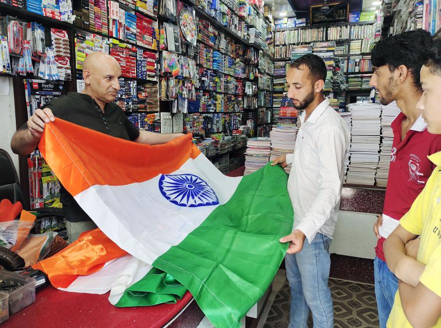 A vendor shows a tri-colour national flag to a customer "Har Ghar Tiranga" campaign ahead of next month's Independence Day celebrations at Mendhar area of Poonch