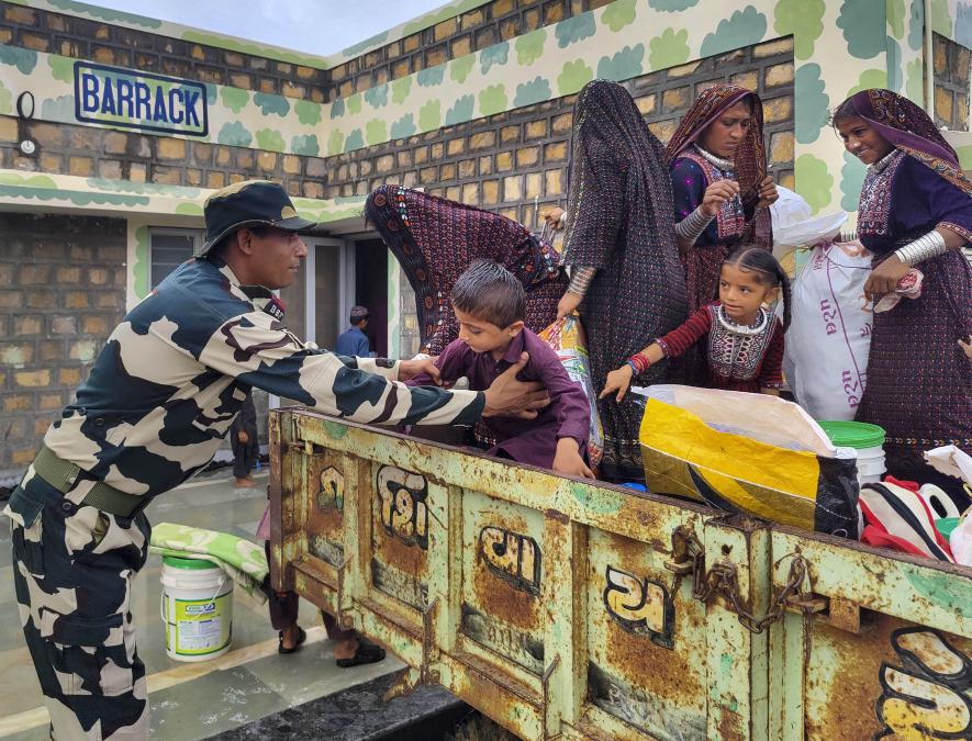 A BSF officer helps a child to get down from a tractor as evacuation process is underway ahead of the expected landfall of Cyclone Biparjoy, at Gunau village of kutch district, Wednesday, June 14, 2023.