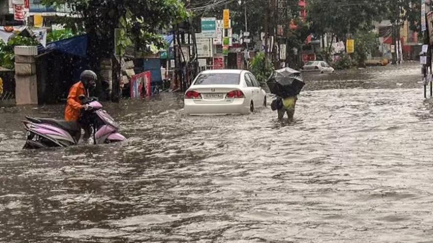 Commuters wade across a water-logged street surrounding the Ernakulam city after monsoon rainfall, in Kochi on Monday, July 16, 2018. 