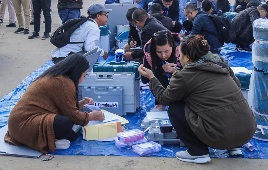 Polling officials collect EVMs and other election material at a distribution centre ahead of voting for Mizoram Assembly elections.