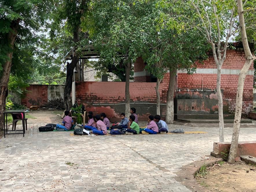 Children attending class under a tree at the government school in Kasandi, Haryana.